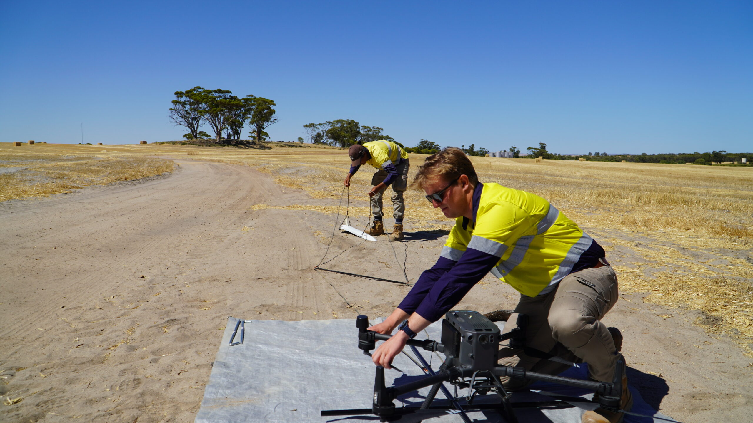 Two Snsorem experts assemble drone equipment on a farm.