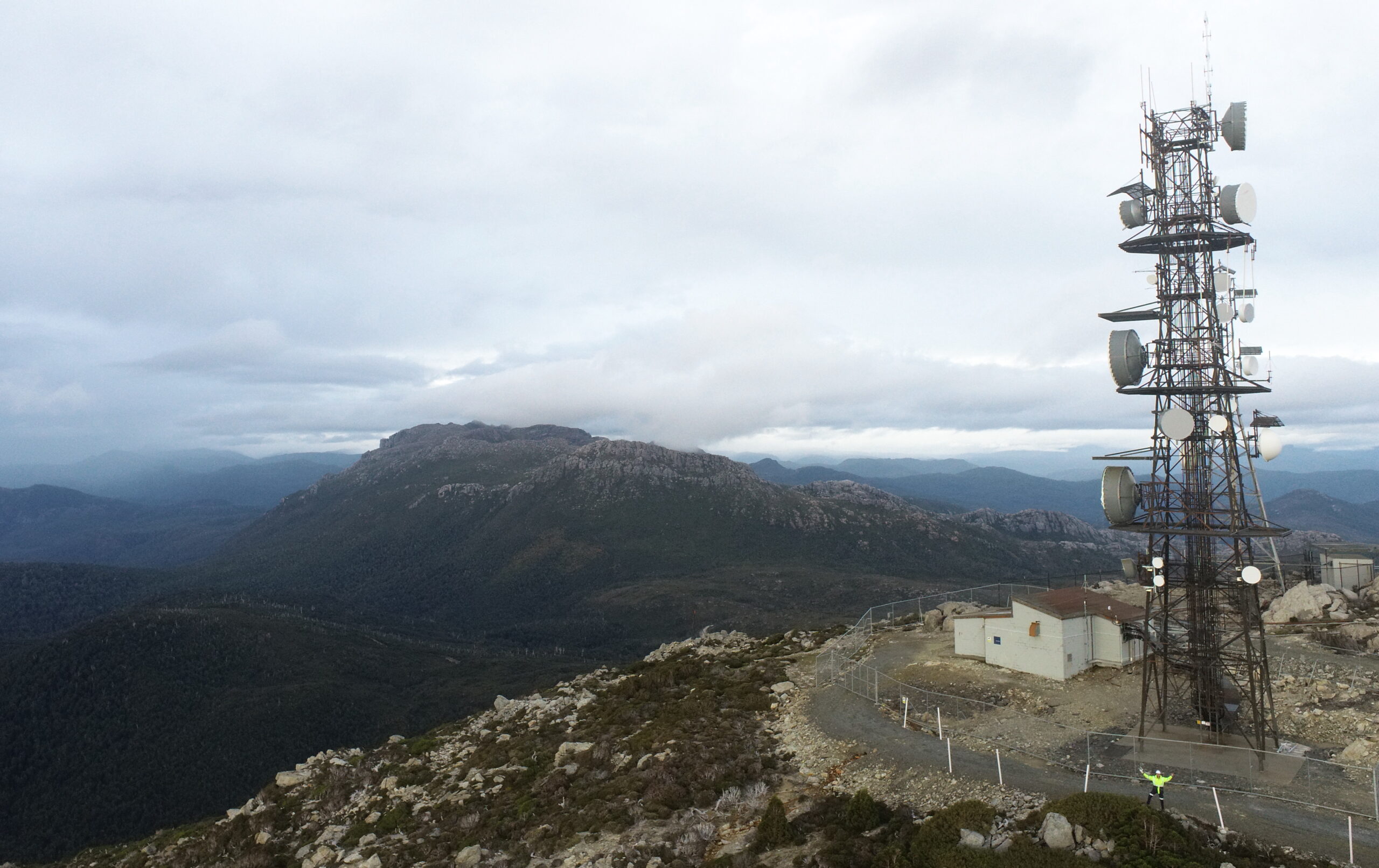 Wide shot of a telecommunication tower overlooking mountains and sky.